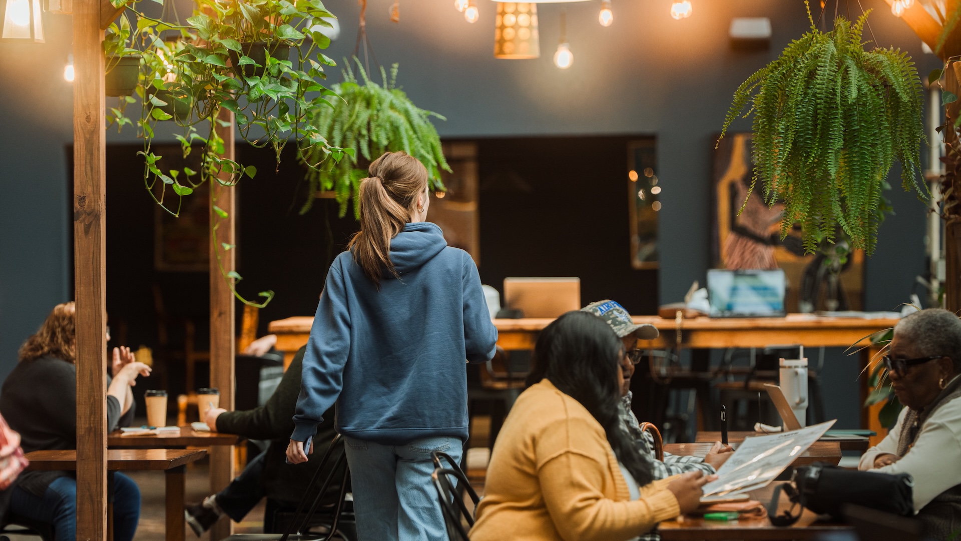 Guests seated in the warm atmosphere of Earth Coffeehouse, surrounded by hanging plants